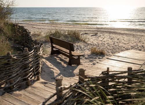 a bench sitting on a wooden path to the beach at Guest House Skrablas in Rucava