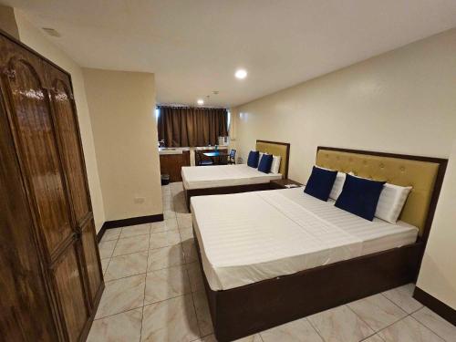 two beds in a hotel room with blue pillows at Suntal Residences in Bacolod