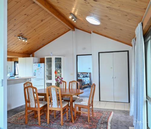 a kitchen and dining room with a wooden ceiling at Sunny Beachview Homestay Auckland in Auckland