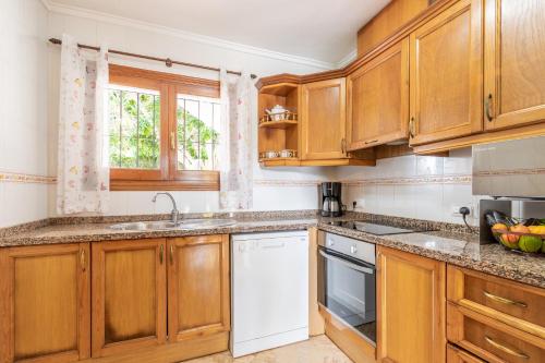 a kitchen with wooden cabinets and a white dishwasher at La Boniquesa in Benissa