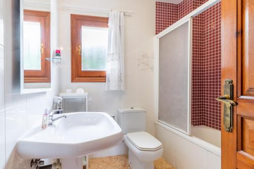 a white bathroom with a toilet and a sink at La Boniquesa in Benissa