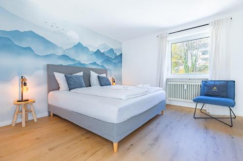 a bedroom with a bed and a blue chair at AUSZEIT am ALPSEE - Wohlfühloase auf 69 m2 in Immenstadt im Allgäu