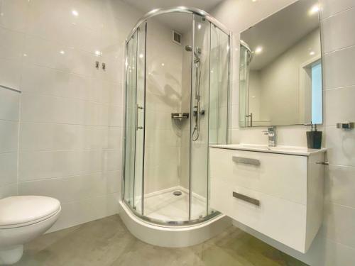 a white bathroom with a shower and a toilet at Apartamenty Szóstka Wisła Kamienna in Wisła