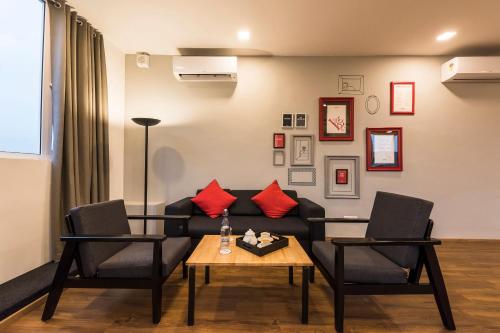 a living room with a couch and two chairs and a table at Townhouse MG Road,Bangalore in Bangalore