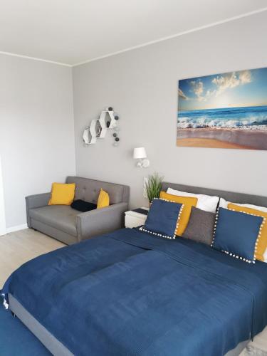 a bedroom with a blue bed and a couch at Aquamarina Onyx Seaside in Międzyzdroje