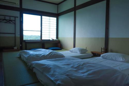 three beds in a room with two windows at Kaya Yamanoie in Yosano