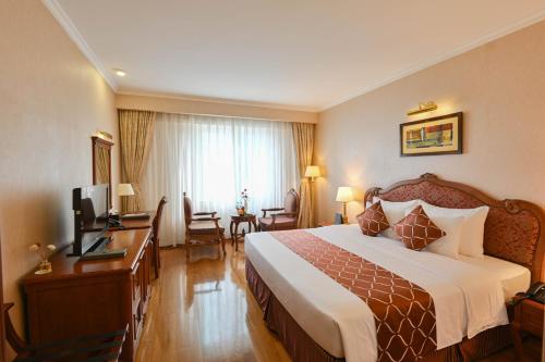 a hotel room with a bed and a desk and a television at Hotel Grand Saigon in Ho Chi Minh City