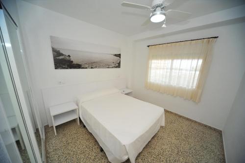 a white bedroom with a bed and a window at Estoril III vista mar Orangecosta in Benicàssim