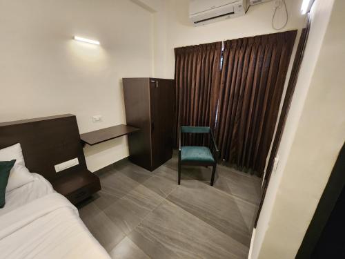 a bedroom with a bed and a chair and a window at Udupi Comforts in Udupi