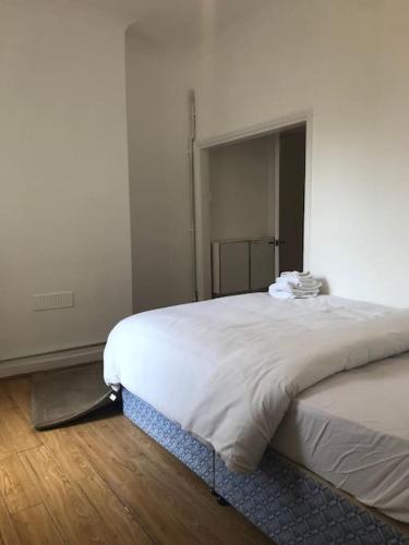 - un lit blanc dans une chambre avec un miroir dans l'établissement Lovely 1 bed flat in great location with garden, à Ilford