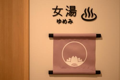 a sign for a bathroom with a mirror and asian symbols at SAKURA PORT HOTEL in Kitakami