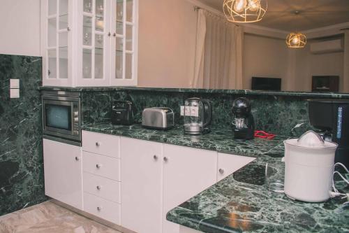a kitchen with white cabinets and a green counter top at Theasis Luxury Apartment in Nafplio