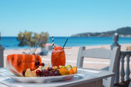 a plate of fruit on a table with a drink at Marini Seaside in Faliraki