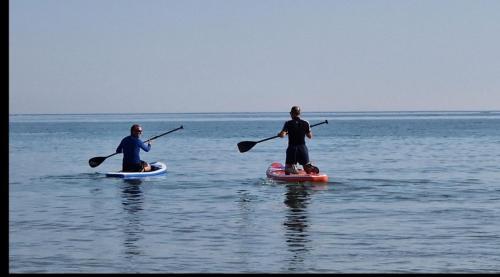 two people are on paddle boards in the water at Guest suite 50m from the beach in Bognor Regis