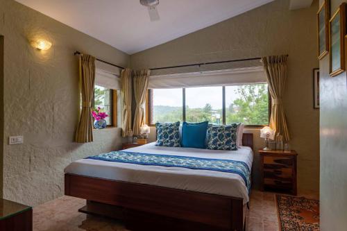 - une chambre avec un lit doté d'oreillers bleus et d'une fenêtre dans l'établissement ama Stays & Trails Dulwich Terrace, Panchgani, à Panchgani