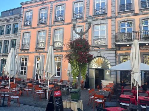 een groep tafels en stoelen voor een gebouw bij Le Vieux Cèdre Grand Place in Bergen