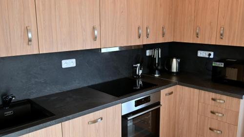 a kitchen with wooden cabinets and a black counter top at Apartmány Smrkový vrch in Vaclavov u Bruntalu