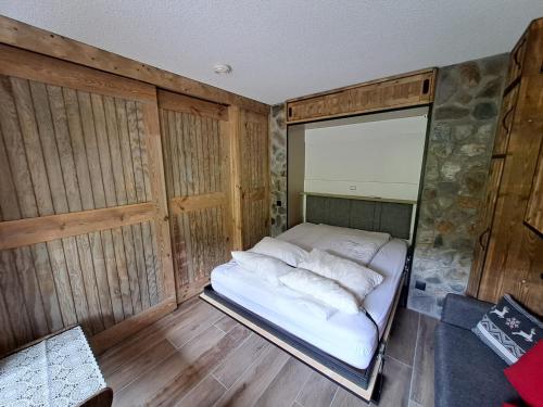 Ce petit lit se trouve dans un dortoir doté de murs en bois. dans l'établissement HSL, à Valmorel