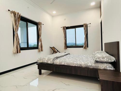 um quarto com uma cama e duas janelas em Govardhan villas Guest House & Farm Stay em Bijāpur