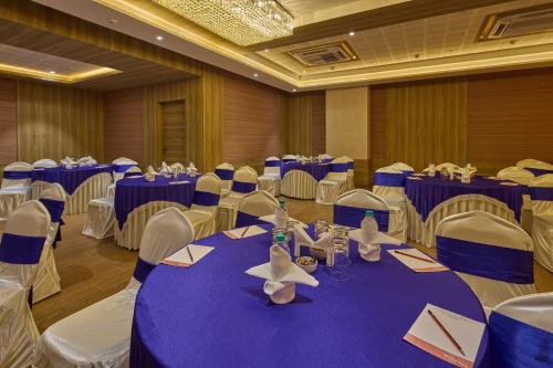 a banquet hall with blue tables and white chairs at Grand Continent Hosur A Sarovar Portico Affiliate Hotel in Hosūr