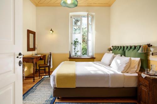 um quarto com uma cama, uma secretária e uma janela em Archontiko Parnassus Dadi em Amfikleia