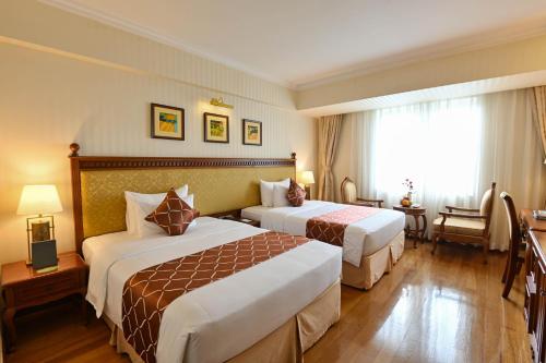 a hotel room with two beds and a window at Hotel Grand Saigon in Ho Chi Minh City