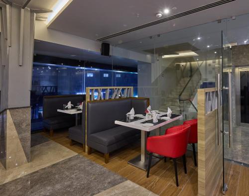 a restaurant with two tables and red chairs at Grand Continent Hosur A Sarovar Portico Affiliate Hotel in Hosūr
