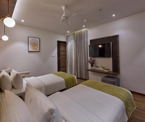 a hotel room with two beds and a flat screen tv at Grand Continent Hosur A Sarovar Portico Affiliate Hotel in Hosūr