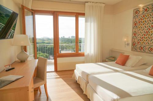 1 Schlafzimmer mit 2 Betten, einem Schreibtisch und einem Fenster in der Unterkunft Art&Park Hotel Union Lido in Cavallino-Treporti