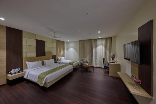 a hotel room with a large bed and a television at Grand Continent Hosur A Sarovar Portico Affiliate Hotel in Hosūr
