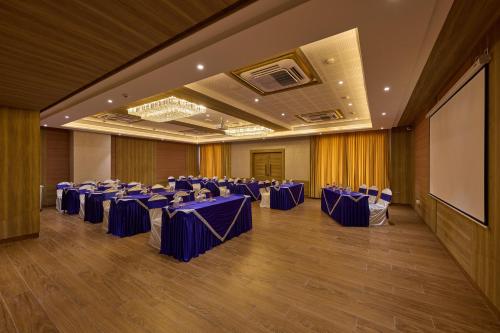 a banquet hall with blue tables and chairs and a screen at Grand Continent Hosur A Sarovar Portico Affiliate Hotel in Hosūr