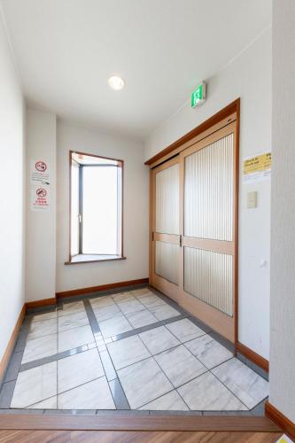 an empty room with a door and a window at The COMFORIA in Sapporo