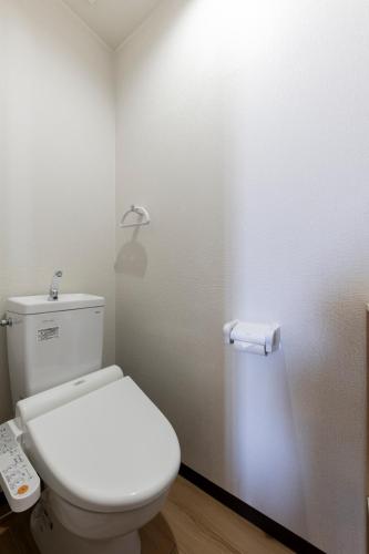 a bathroom with a toilet with a light on the wall at The COMFORIA in Sapporo