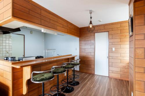 a kitchen with wooden walls and bar stools at The COMFORIA in Sapporo