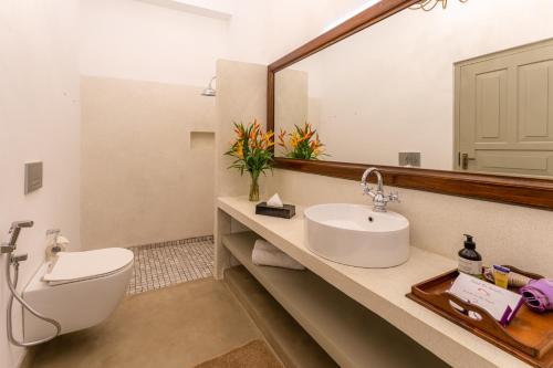 a bathroom with a sink and a toilet and a mirror at The Fort House in Galle