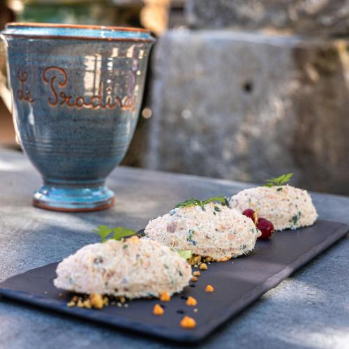 a black plate with food on a table with a glass at Logis Hôtel Restaurant Le Pradinas in Anduze