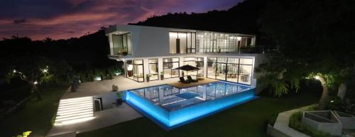 une grande maison avec une piscine la nuit dans l'établissement Sisid Anilao Resort, à Mabini