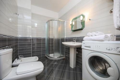 a bathroom with a toilet a sink and a washing machine at Noa Apartments in Vlorë