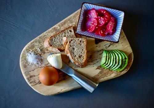 una tabla de cortar de madera con pan y verduras. en Theoreion, en Tholária