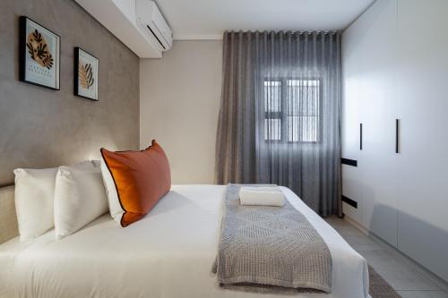 a bedroom with a white bed and a window at The Tyne Luxury Apartments in Durban