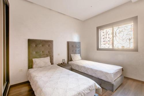 1 dormitorio con 2 camas y ventana en Appartement résidence Marrakech haut standing piscine, en Marrakech