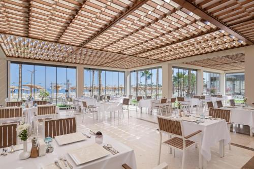 a restaurant with white tables and chairs and windows at Xanadu Makadi Bay - High Class All Inclusive in Hurghada