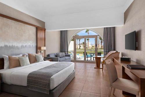 a hotel room with a large bed and a desk at Xanadu Makadi Bay - High Class All Inclusive in Hurghada