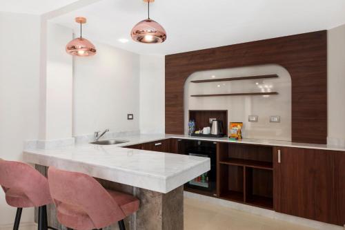 a kitchen with a counter and some pink chairs at Xanadu Makadi Bay - High Class All Inclusive in Hurghada