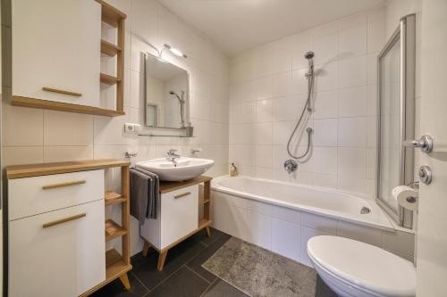 a bathroom with a sink and a tub and a toilet at FaWa Apartments "Family" in Brunico
