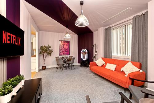 a living room with an orange couch and a table at PRIME City Centre Location, THE JUKE BOX SUITE, Secure Gated FREE Parking Space, Unique STYLISH Apartment, AIR CONDITIONING & Two Bathrooms in Milton Keynes