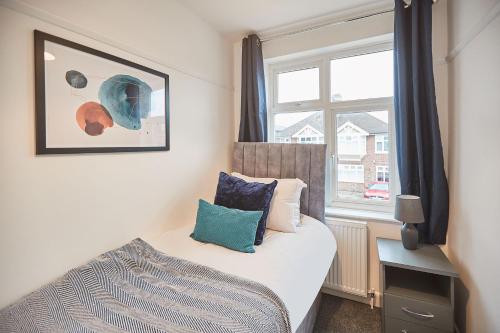 a small bedroom with a bed and a window at Elfleda Stay - Modern 5 bedroom house with parking in Cambridge
