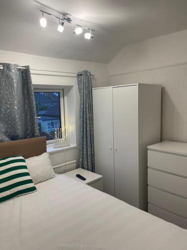 a bedroom with a bed and a cabinet and a window at Spare room in a family house in Bristol