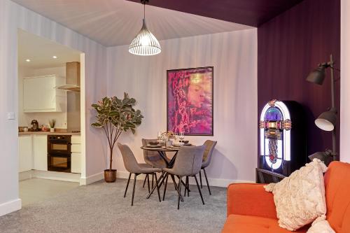 a living room with a table and chairs and a kitchen at PRIME City Centre Location, THE JUKE BOX SUITE, Secure Gated FREE Parking Space, Unique STYLISH Apartment, AIR CONDITIONING & Two Bathrooms in Milton Keynes