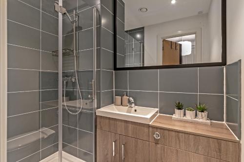 a bathroom with a shower and a sink and a mirror at PRIME City Centre Location, THE JUKE BOX SUITE, Secure Gated FREE Parking Space, Unique STYLISH Apartment, Two Bathrooms in Milton Keynes